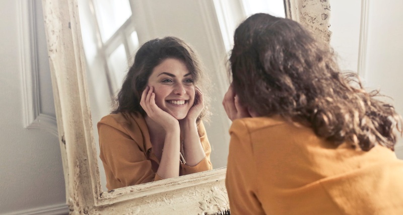 Woman looking in the mirror - koerperzufriendenheit